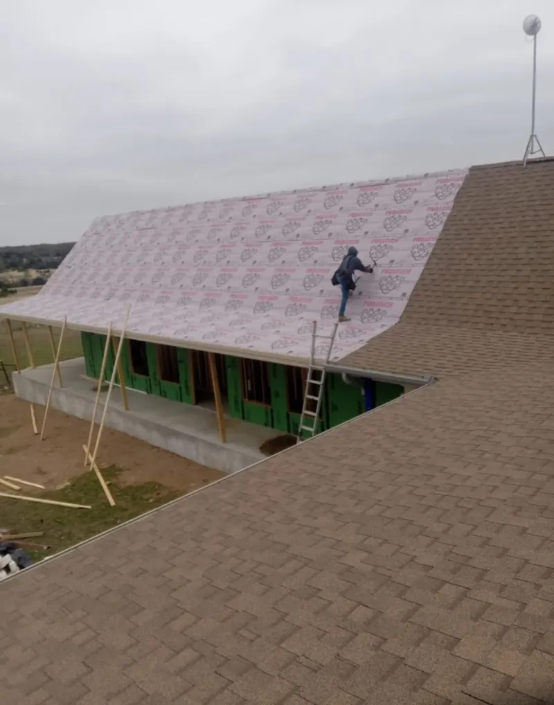 Worker preparing underlayment for a metal roof installation in Mapleton